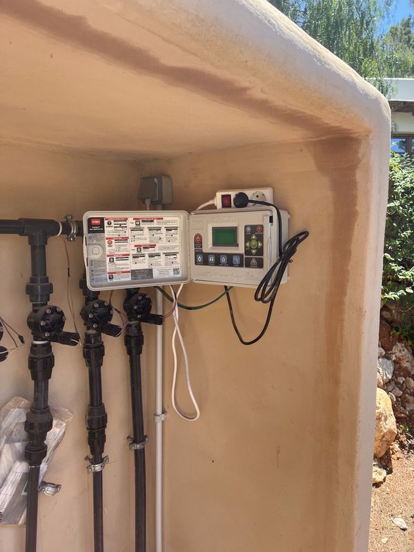Un programador de riego y un colector de válvulas instalados en una pared