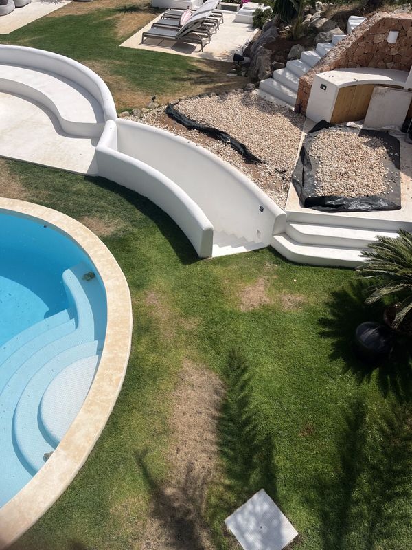 A lawn at Cala Tarida with worn, patchy grass before treatment