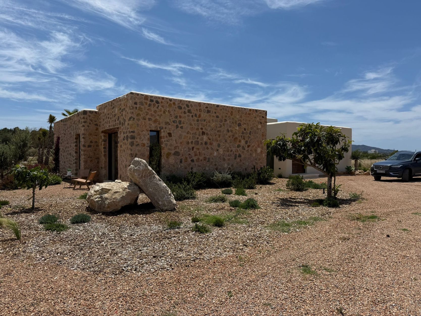 Jardín seco de grava, rocas y plantación baja alrededor de una casa de piedra