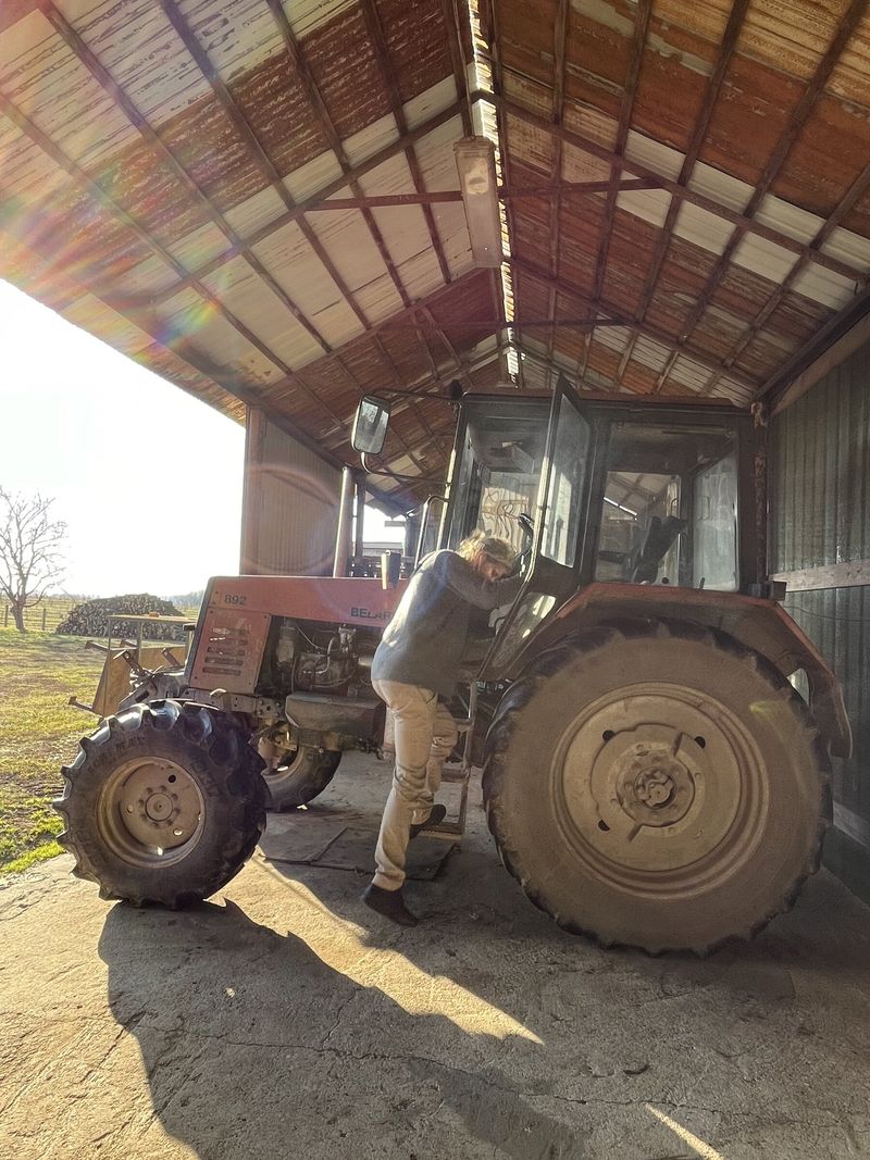 Alguien sube a la cabina de un tractor dentro de un almacén, de espaldas a la cámara
